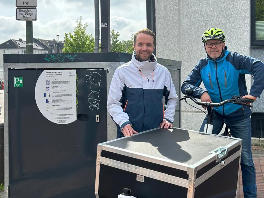 Zwei Männer stehen vor einer Fahrradgarage mit einem elektrisch unterstützten Lastenrad im Sharing-Angebot in Waltrop.